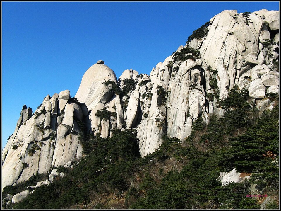 Ridge of rounded and pointed granite peaks above pine forest at Tianzhu Mountain