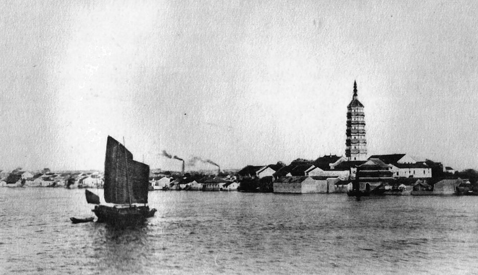 Black and white photo of the Zhenfeng Pagoda rising above the Anqing riverfront with a sailing junk on the Yangtze