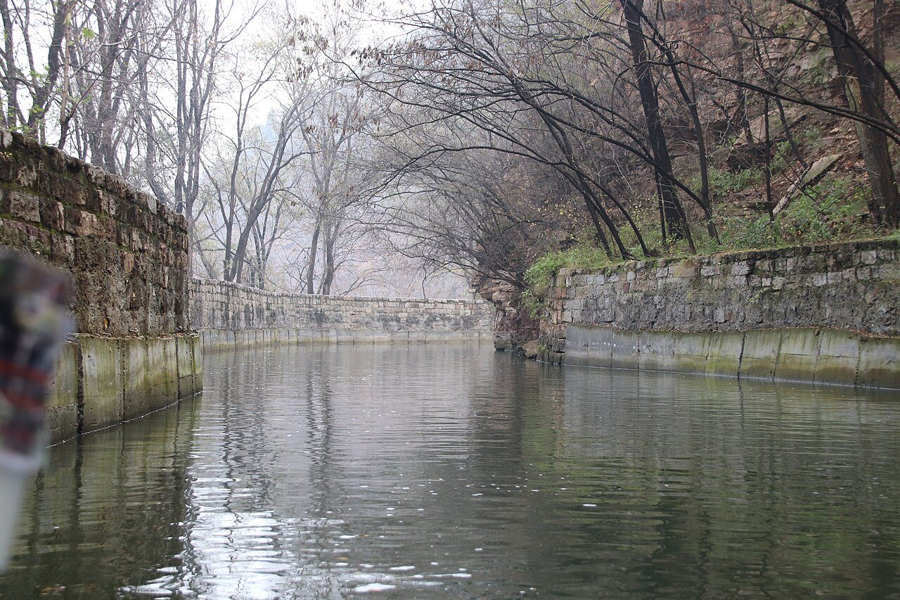 Stone-lined channel of the Red Flag Canal running through bare winter trees in Linzhou