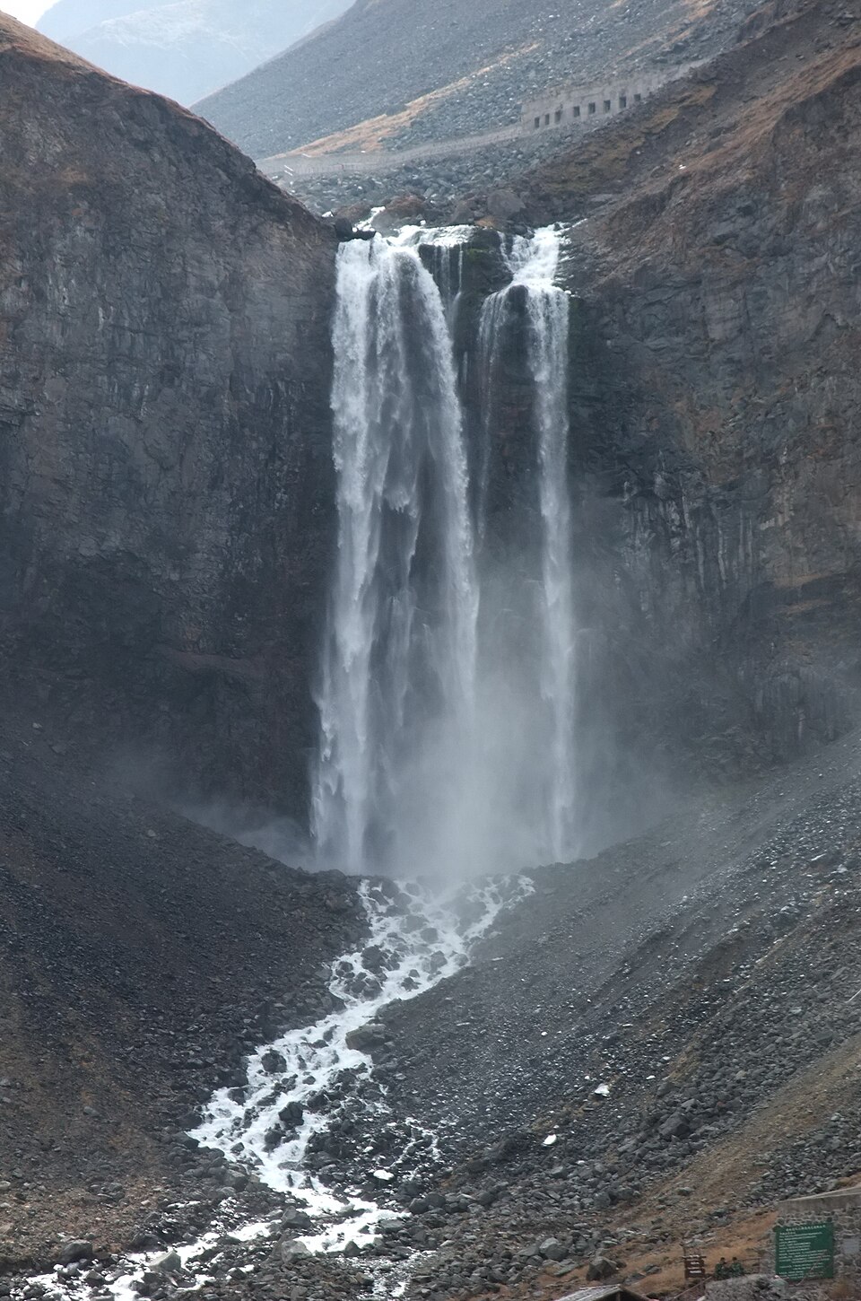 Changbai Waterfall pouring from a cliff below the crater rim into a forested valley