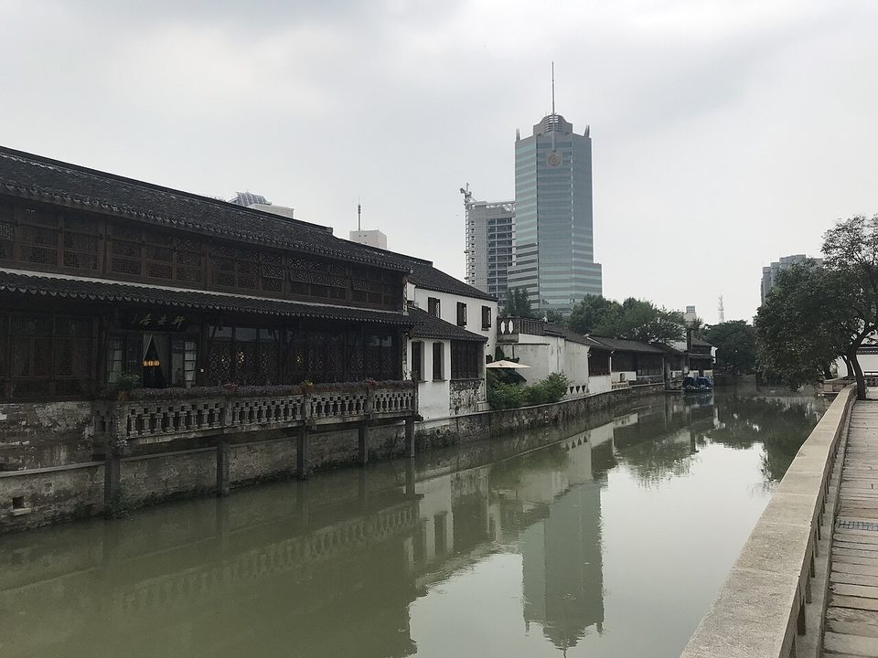 Old houses lining the Nanshi River beside Qingguo Lane with modern towers behind
