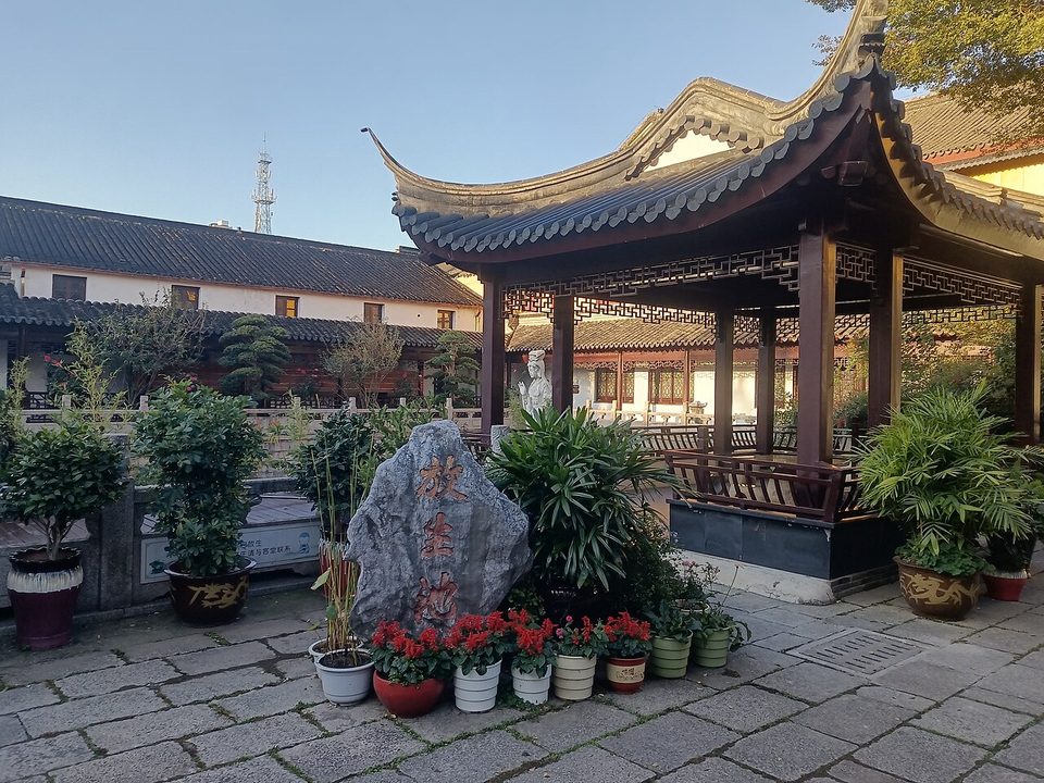Curved roof of a pavilion in the courtyard of Tianning Temple with potted flowers