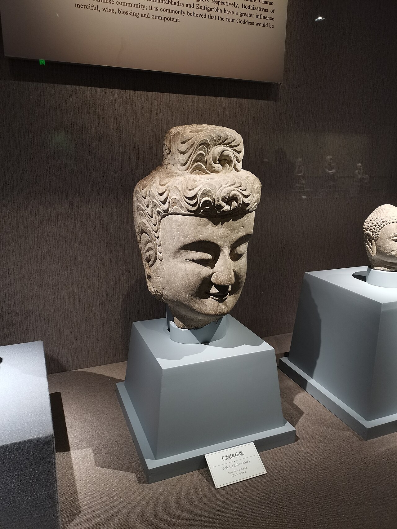 carved stone Buddha head on a plinth in a gallery at Lüshun Museum