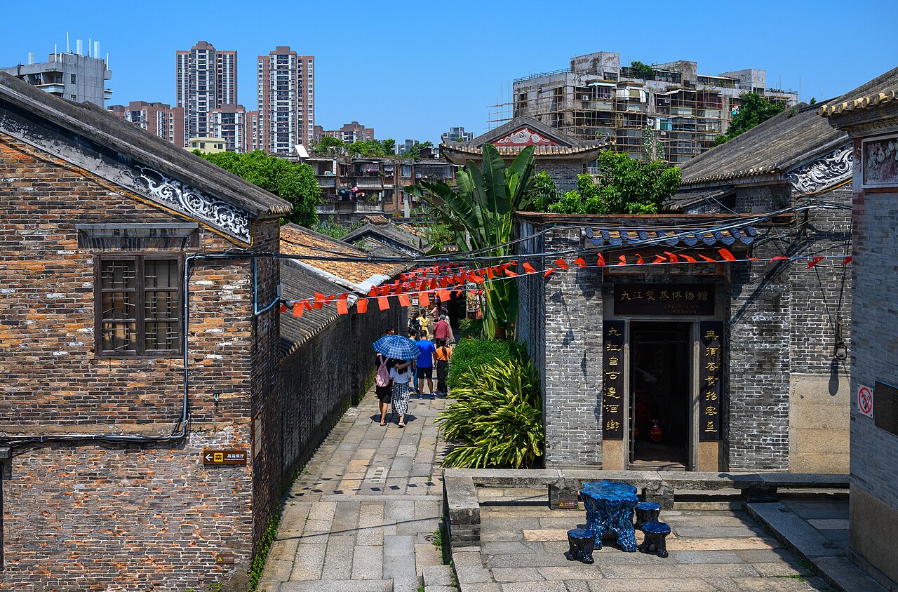 a narrow paved lane between grey brick buildings hung with red lanterns