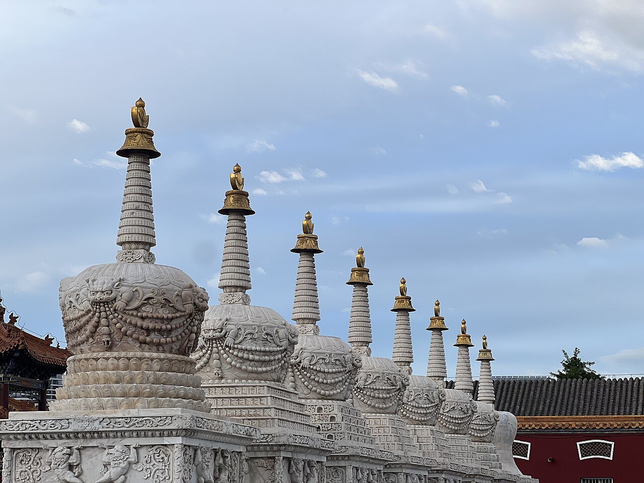 a row of white marble stupas with gold finials outside Dazhao Temple