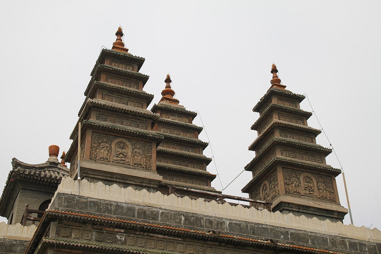 close view of the small square towers on top of the pagoda, covered in rows of carved Buddha niches