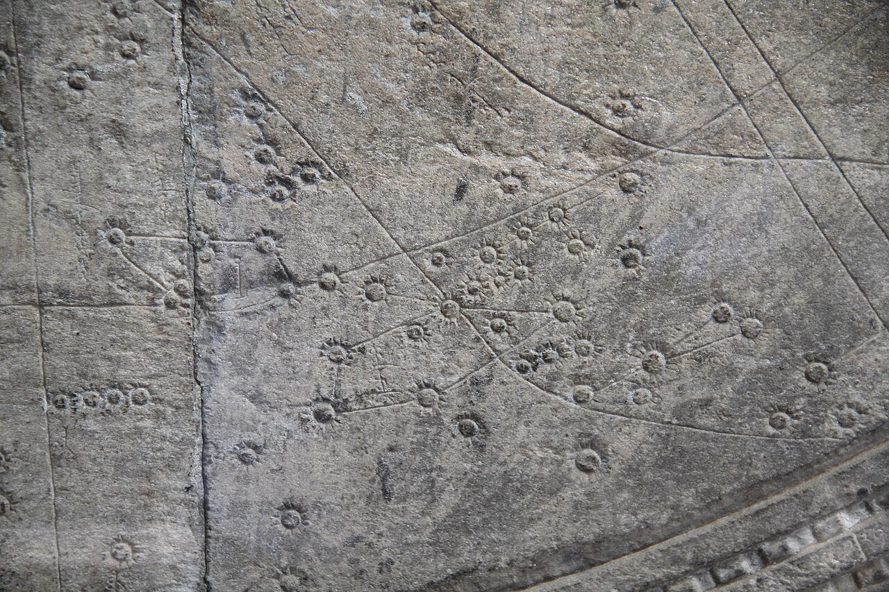 detail of a carved stone star chart showing dotted constellations and curved lines