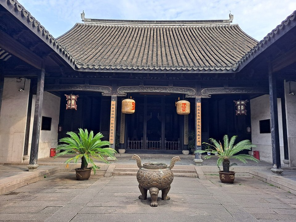 Courtyard of a hall at Little Lotus Manor with potted palms and an incense burner