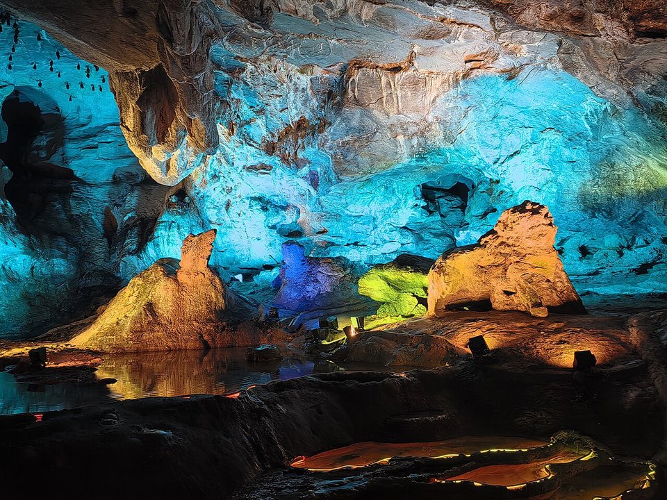 Stalactites lit in blue, gold and green inside Shuanglong Cave