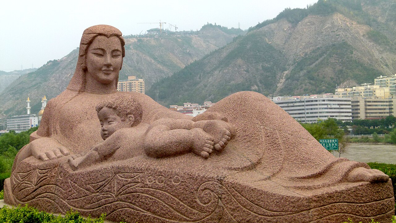 Granite statue of a reclining mother holding a baby beside the Yellow River