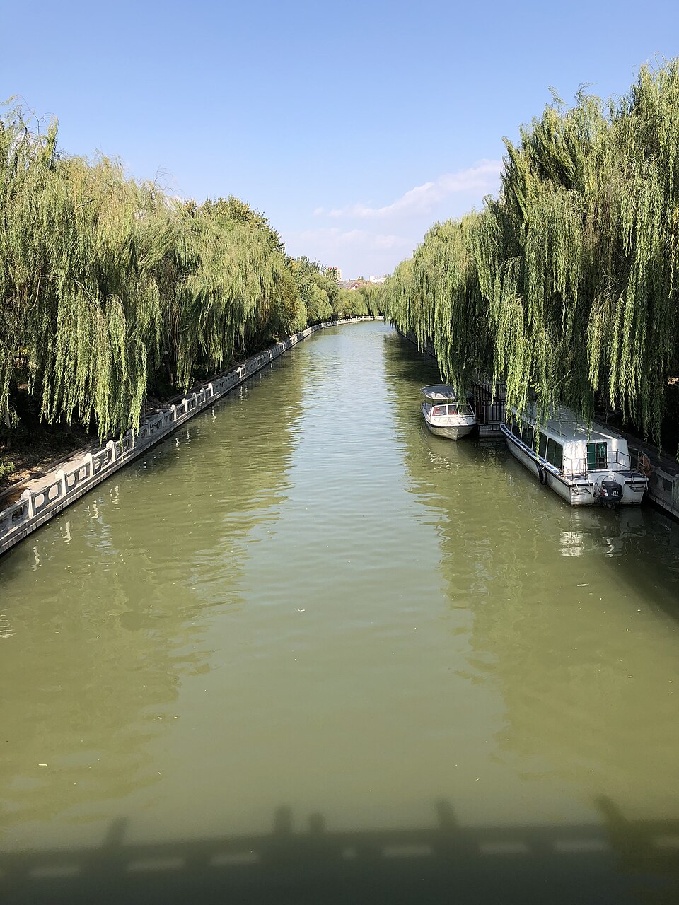 Willow-lined waterway with moored tour boats in Liaocheng