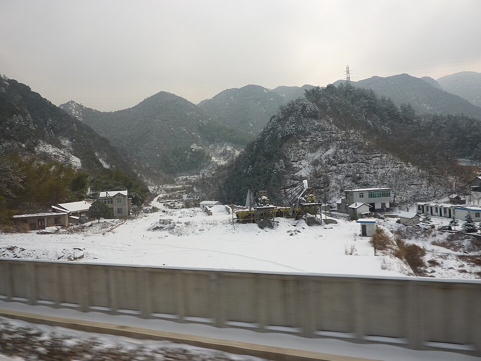 Snow-covered valley village below rocky mountains in the Lu'an area