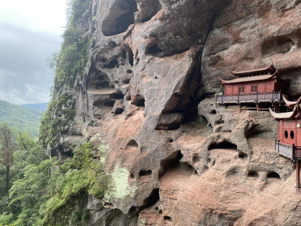 Ganlu Temple's wooden halls built into a cliff overhang above Golden Lake