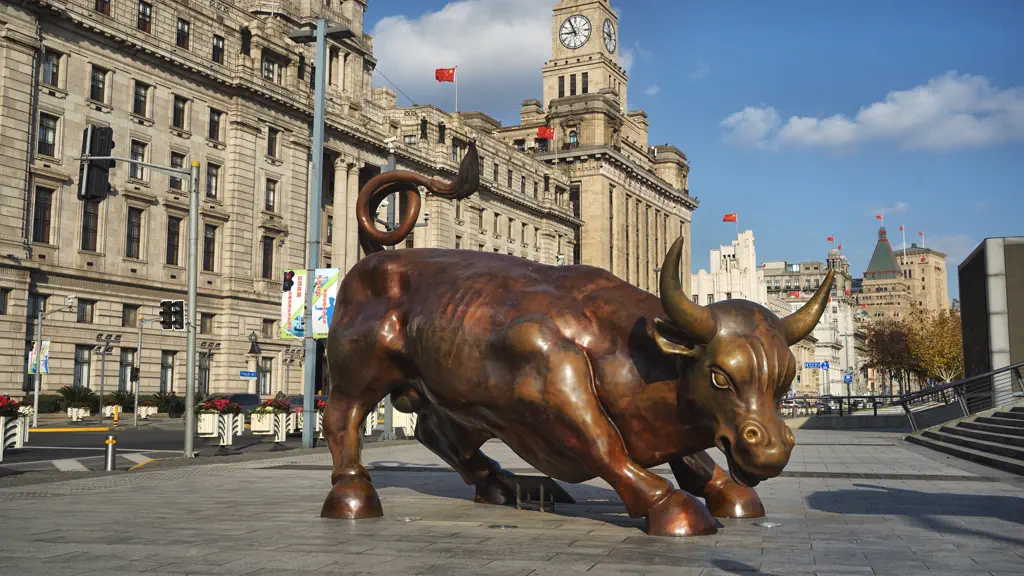 Bronze bull statue on the Bund promenade with historic buildings behind