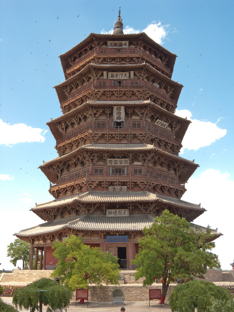 Front view of the Yingxian Wooden Pagoda behind pine trees on a clear day