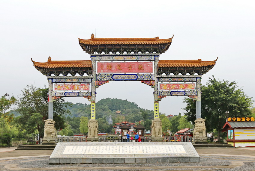Painted memorial archway at the entrance to Guangde Temple, with Wolong Hill behind