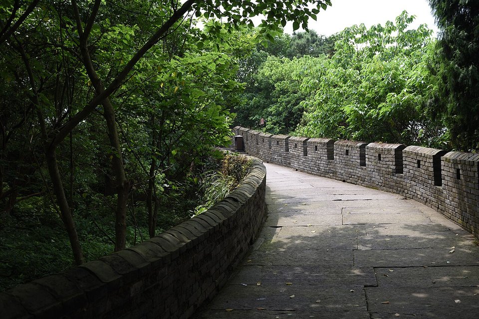 Stone paved walkway along the top of the Linhai city wall with battlements and trees