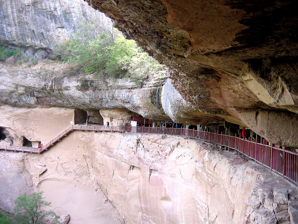 Railed footpath running under an overhanging sandstone cliff at Yuhua Palace