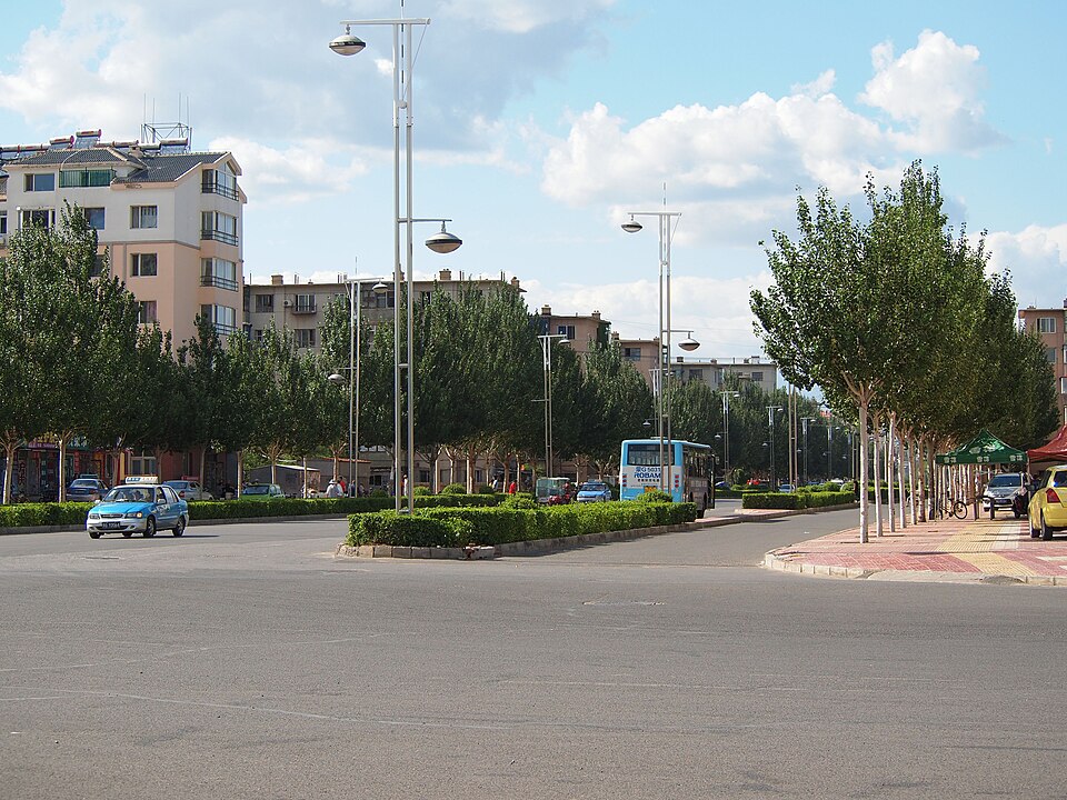 Wide tree-lined street with low apartment blocks in Tongliao