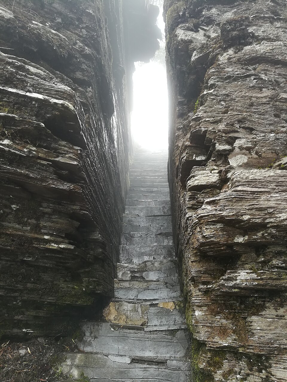 Narrow stone stairway squeezed between sheer layered rock walls on Fanjingshan