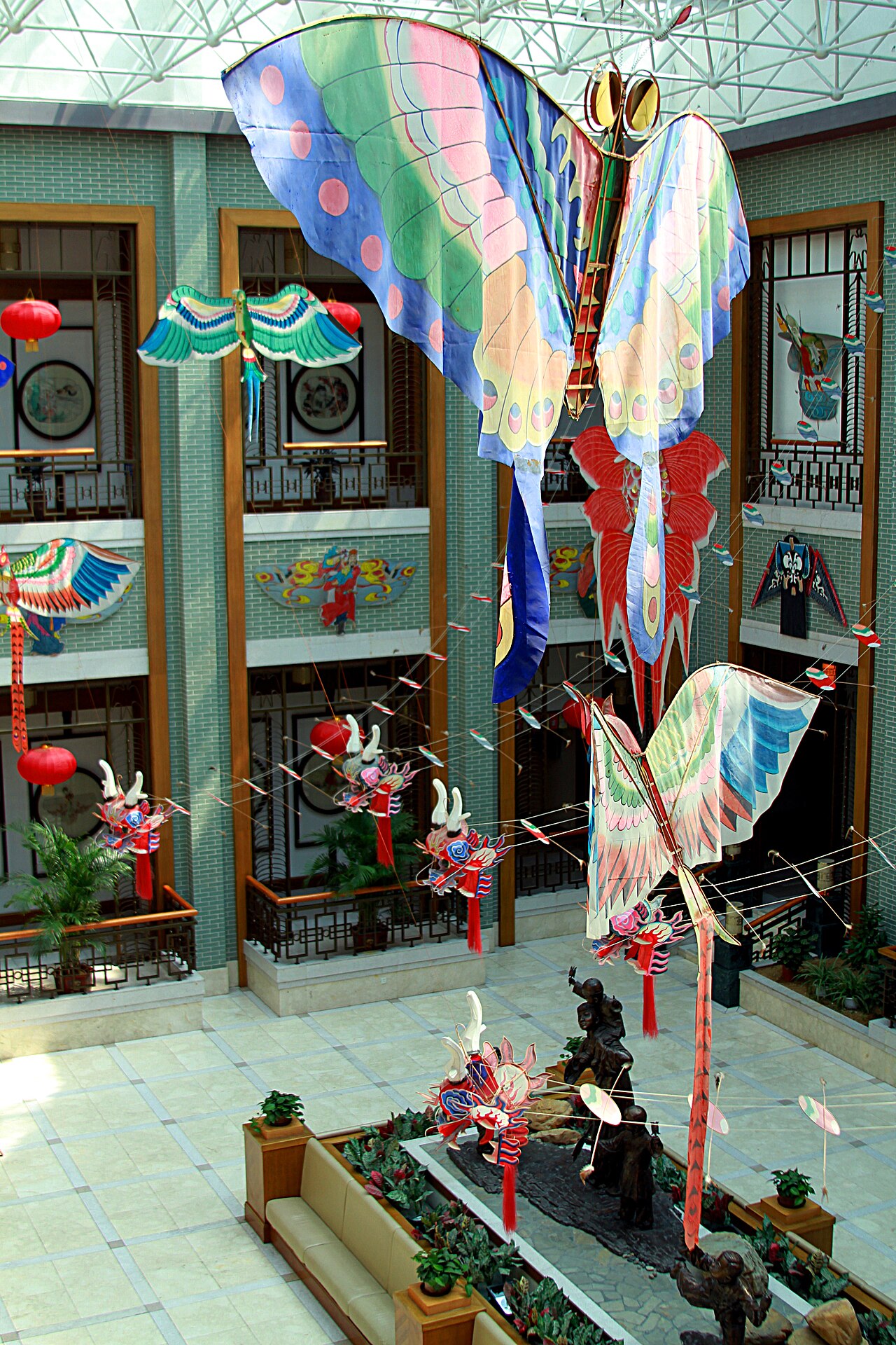 Colourful bird and butterfly kites hanging in the glass-roofed atrium of the Weifang kite museum