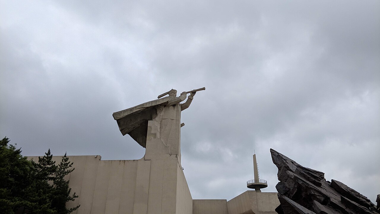 a modern museum building with a sculpture shaped like the bow of a ship and a figure raising a telescope