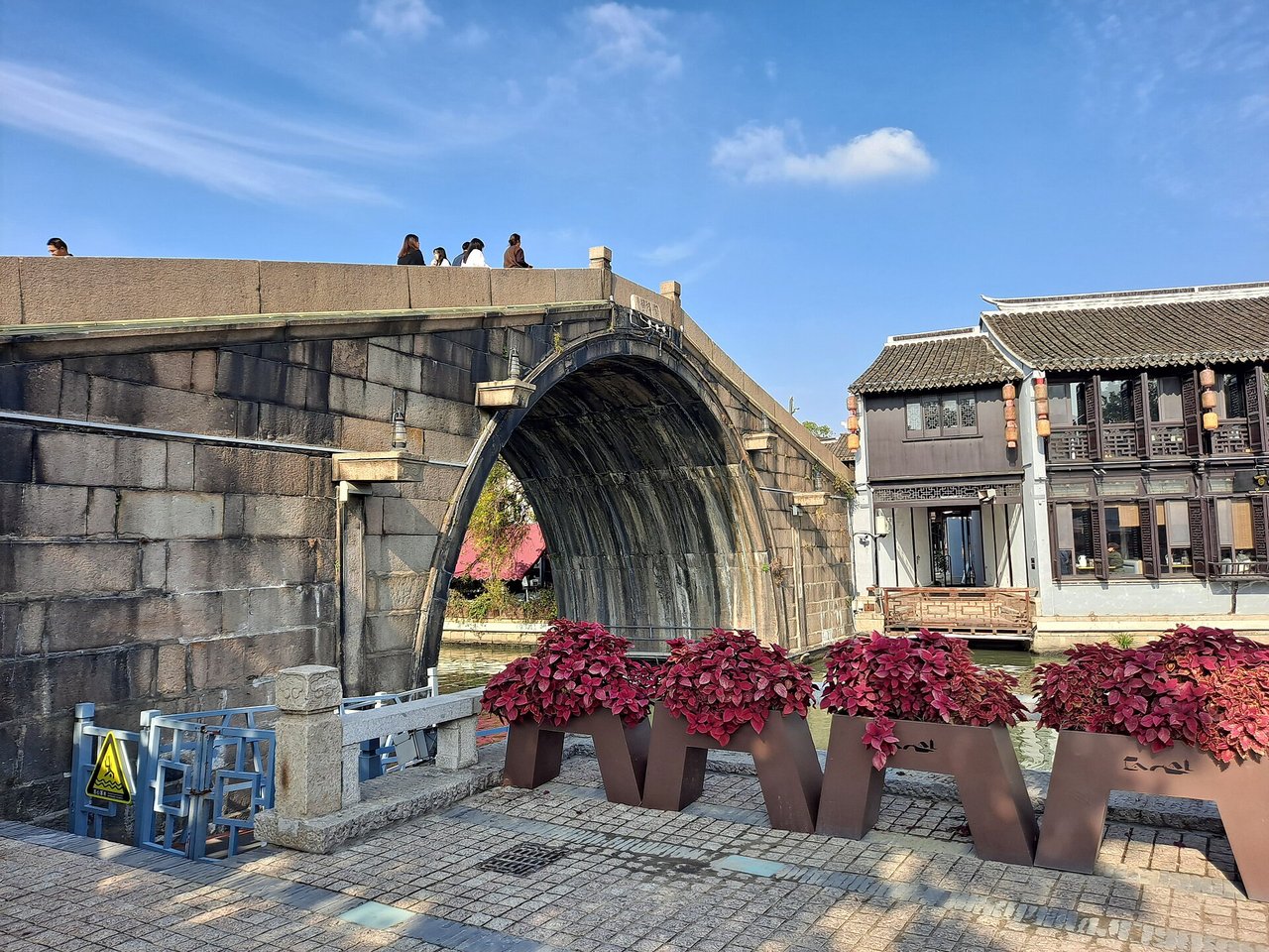 The single stone arch of Qingming Bridge with flowers on the bank