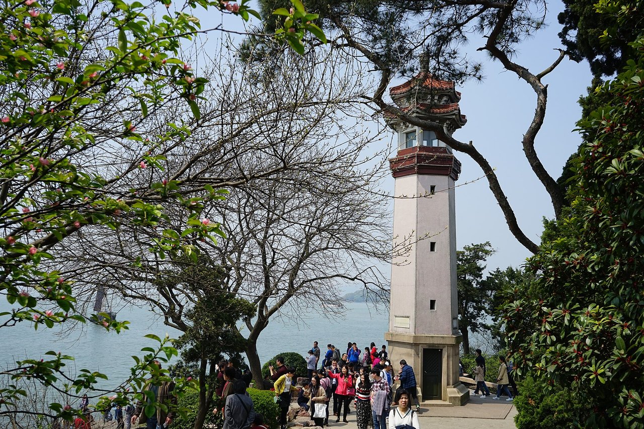 The red and white lighthouse at Yuantouzhu among trees by the lake