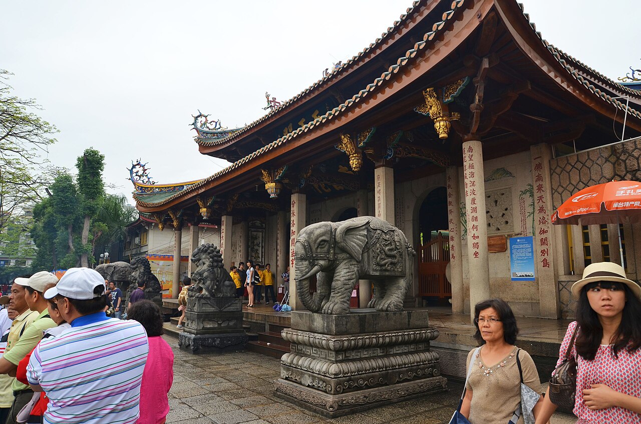 A Nanputuo Temple hall with carved stone elephants and visitors in front