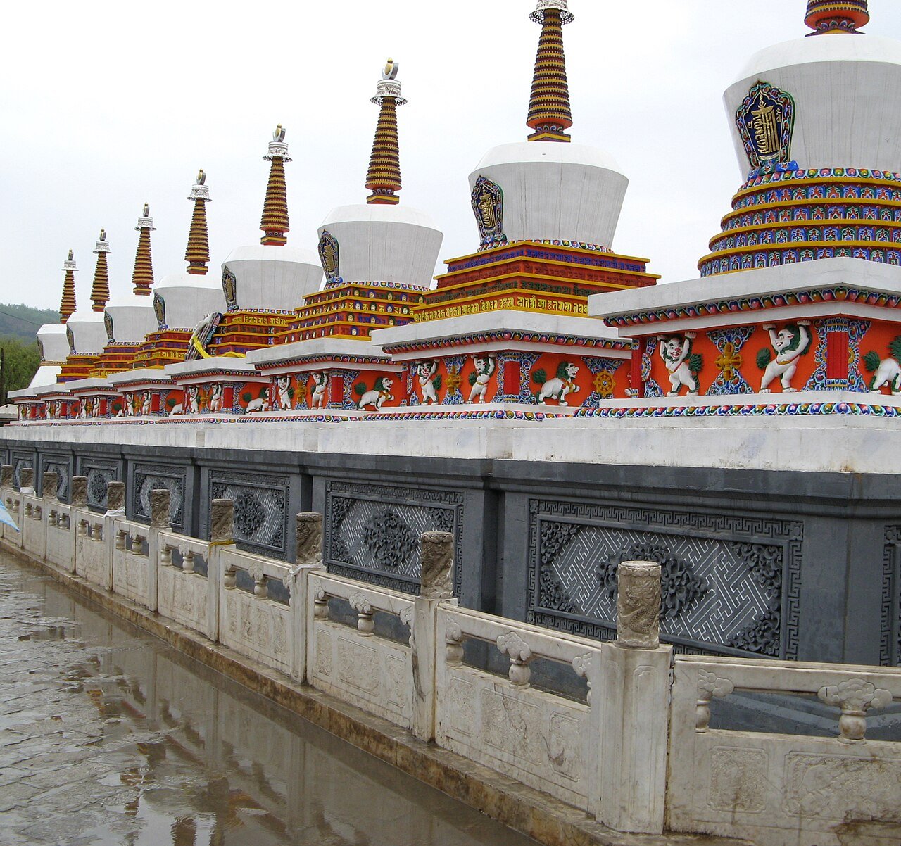 a row of eight white stupas with gold tops and coloured bands at the entrance of Kumbum Monastery