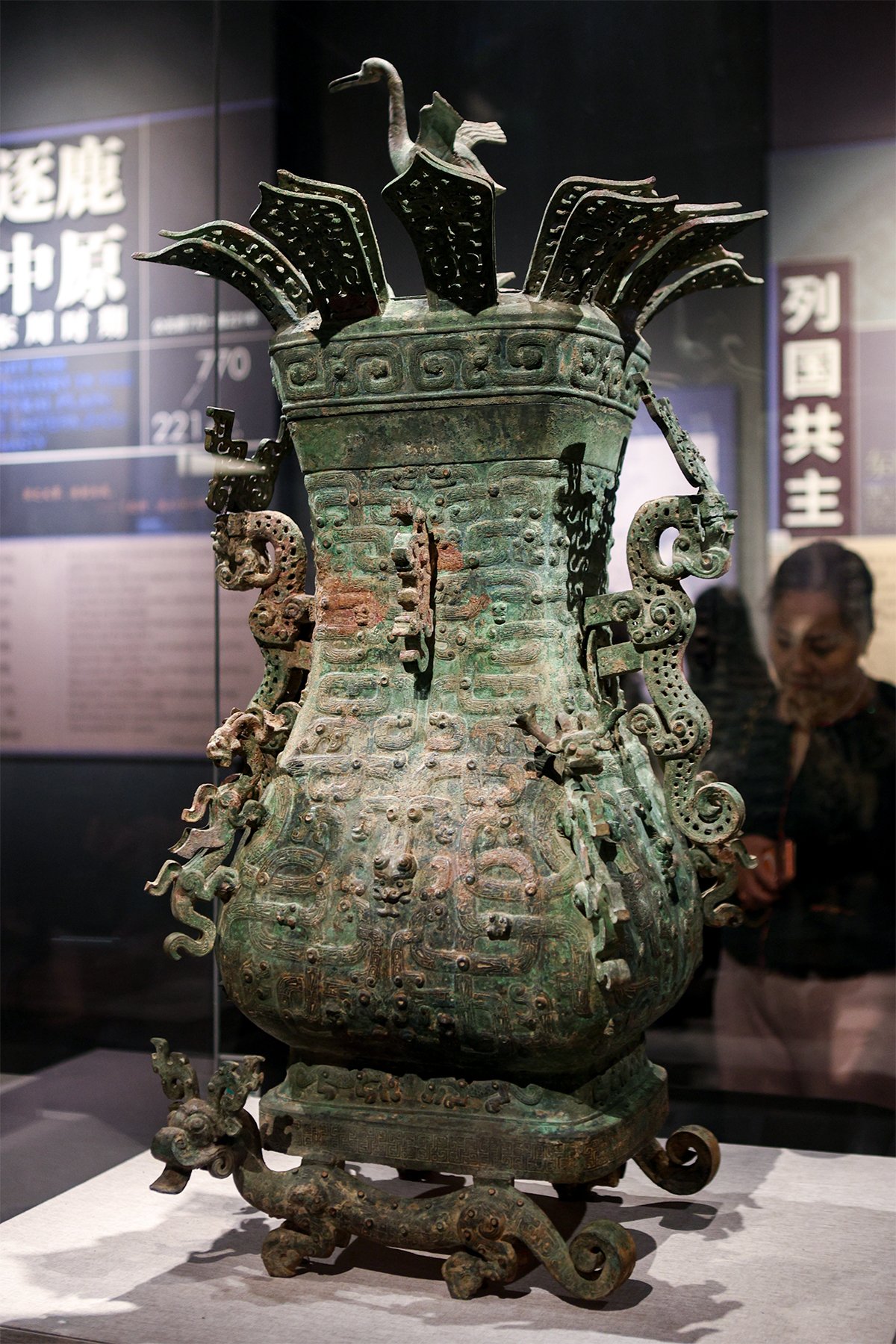 tall bronze square pot topped with lotus petals and a crane